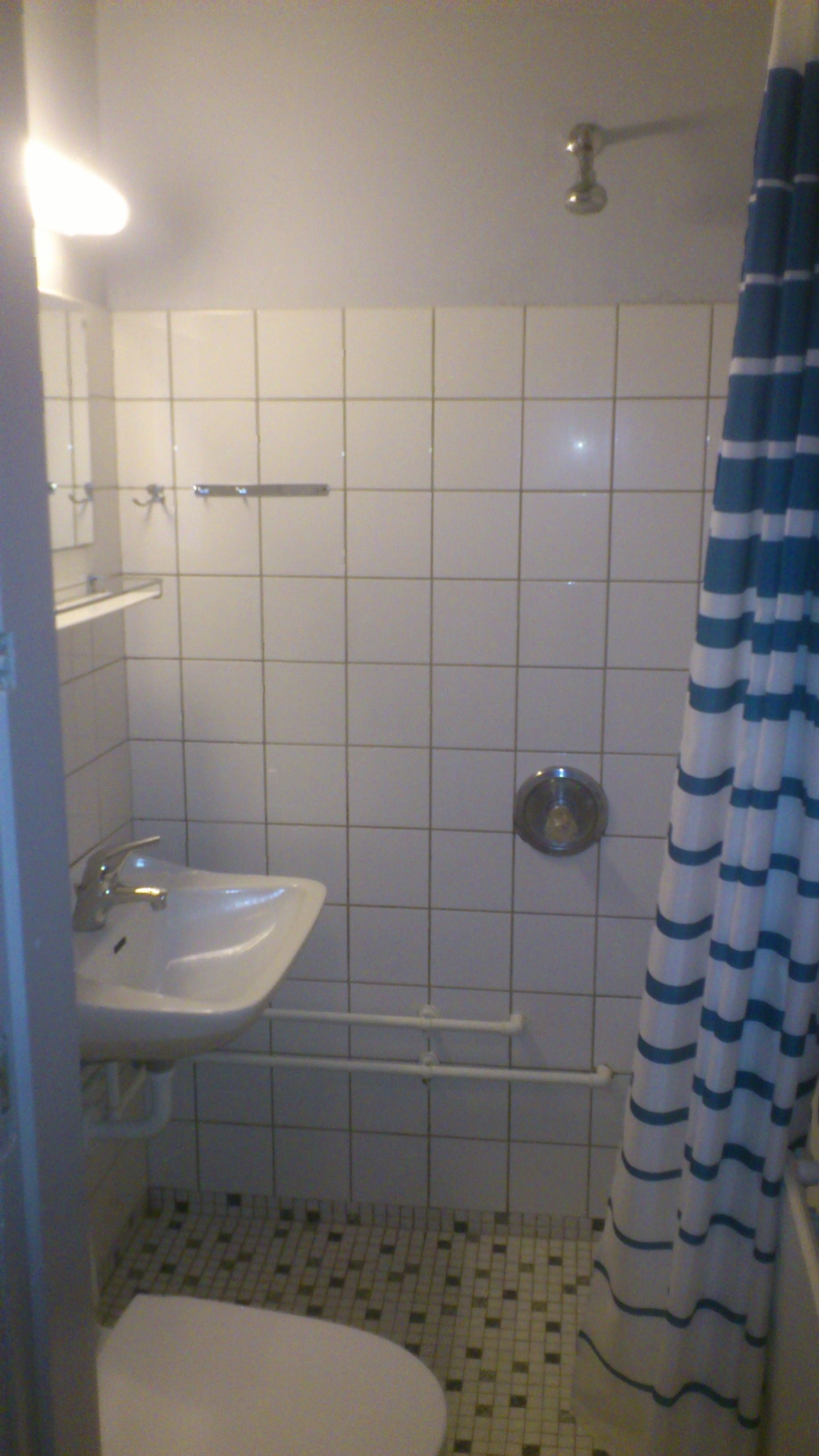 A small bathroom with a white sink, a toilet, and a shower area.