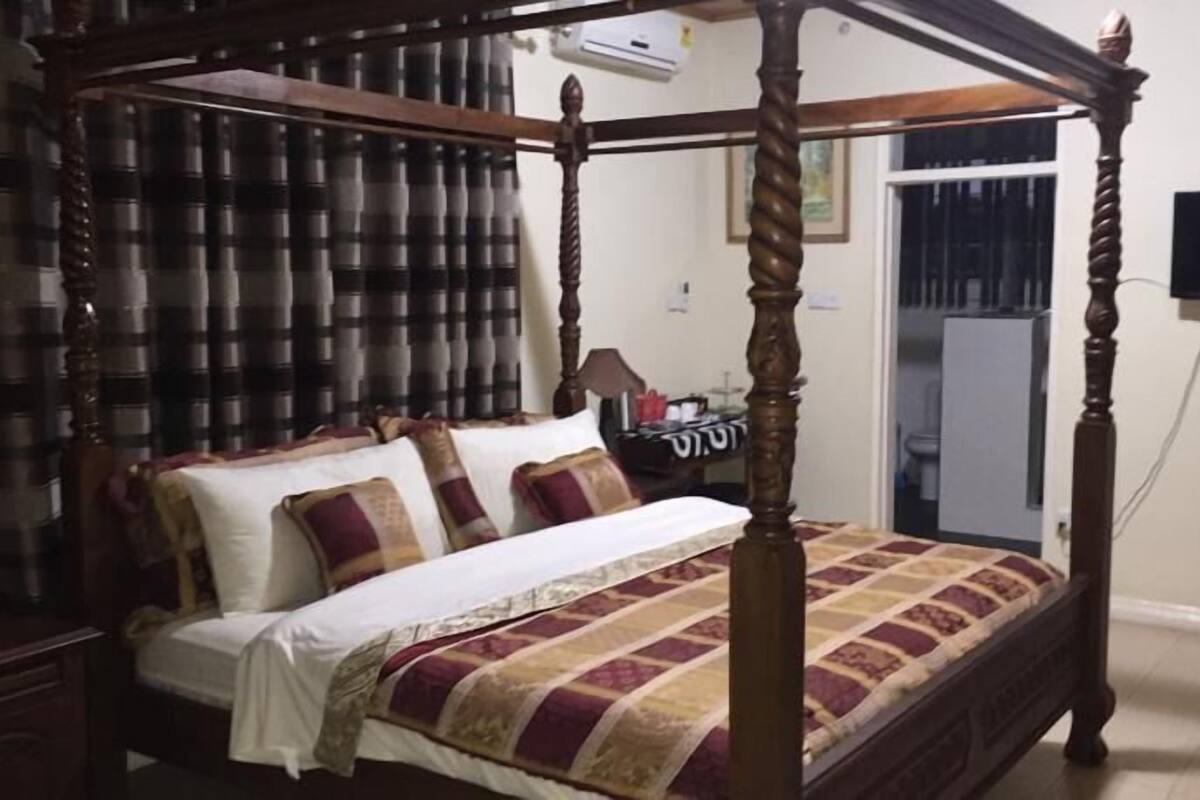 Una cama con dosel de madera, cubrecama blanco y varias almohadas.