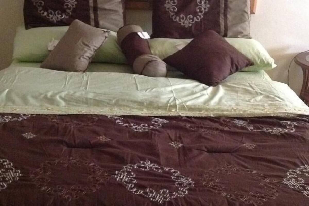 Una cama con una colcha estampada y almohadas.