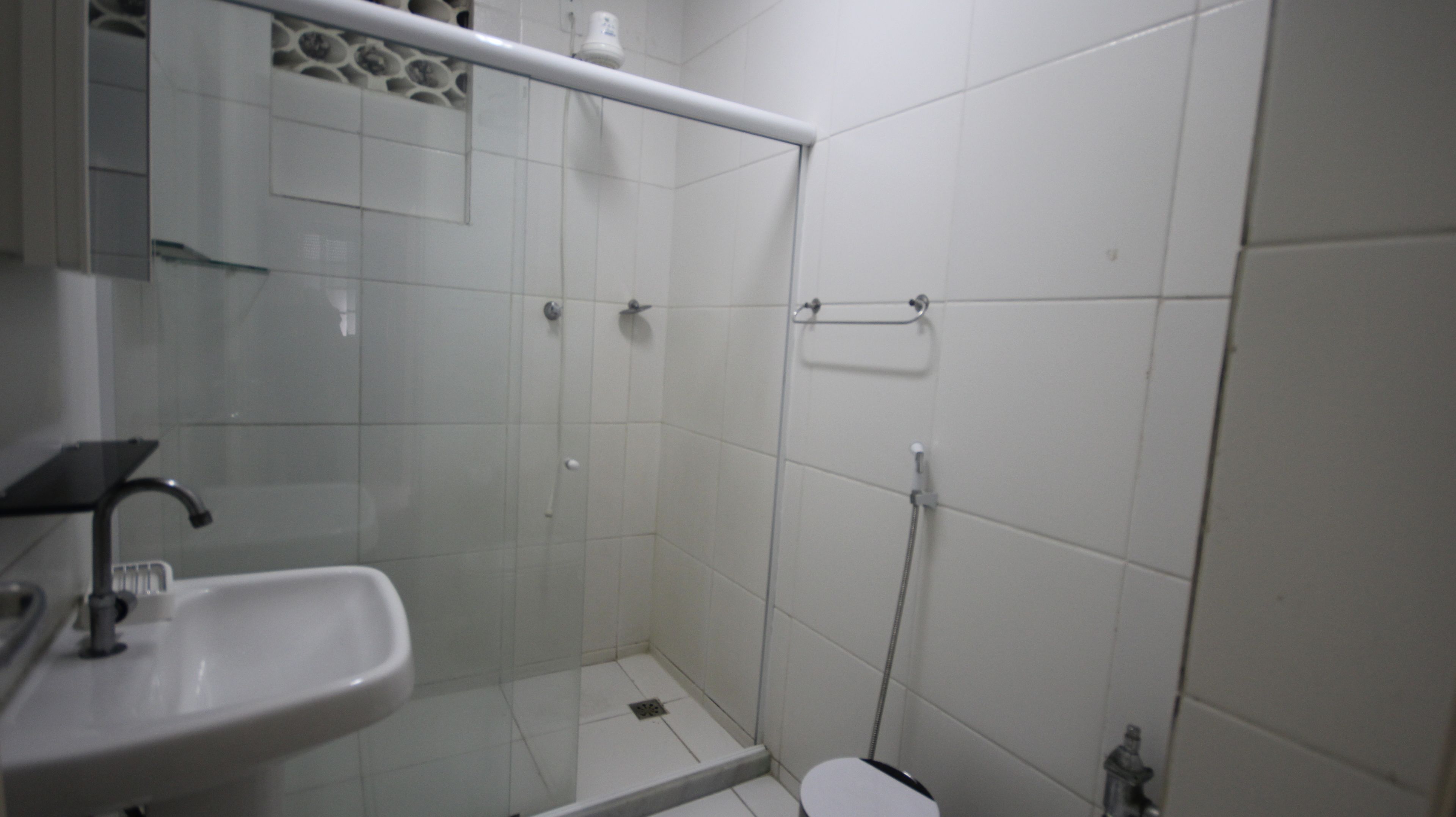 Un baño con lavamanos, cabina de ducha de vidrio y retrete.
