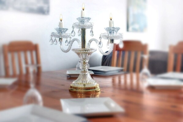 A dining table with a crystal candelabra centerpiece, surrounded by wooden chairs. - Cobblestone Bed and Breakfast (Niagara-on-the-Lake)