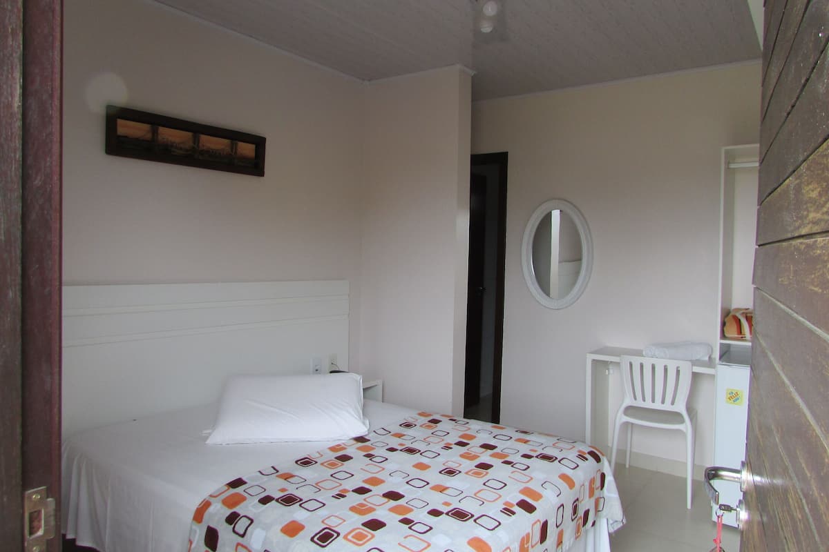 A bedroom with a bed, a desk, and a chair.