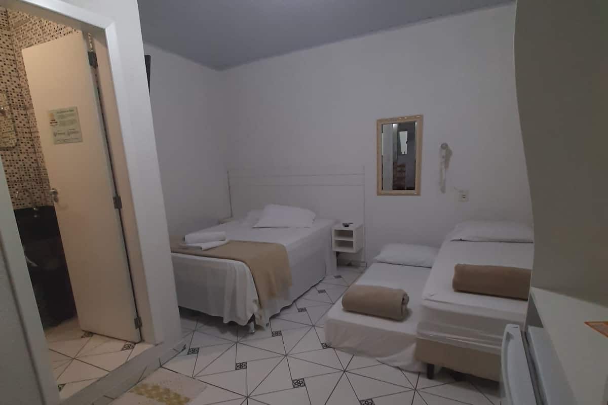 A room with two beds, a small bedside table, a mirror, and a ceiling light.