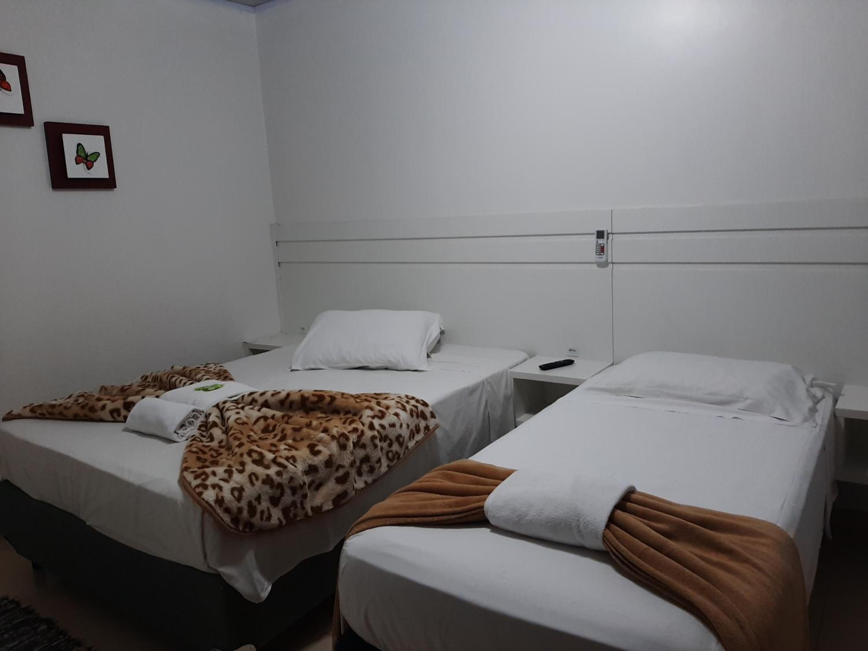 Una habitación con dos camas individuales, cada una con almohada y manta blancas. Hay dos cuadros en la pared.