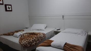 Una habitación con dos camas individuales, cada una con almohada y manta blancas. Hay dos cuadros en la pared.