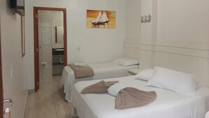 Een hotelkamer met twee bedden, een schilderij van een zeilboot, een televisie en een zichtbare badkamer door een open deur.