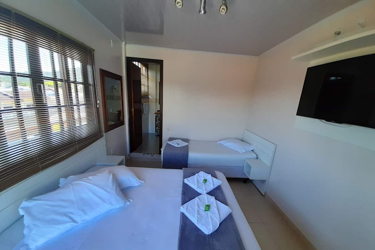 A hotel room with two beds, a TV, and a bathroom visible through an open door.