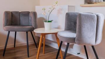 A modern room with two grey upholstered chairs, a small round table, and a potted orchid.