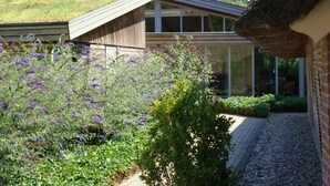 A modern building with a sloped roof, a glass facade, and a garden with purple flowers. - Landhotel Diever (Diever)