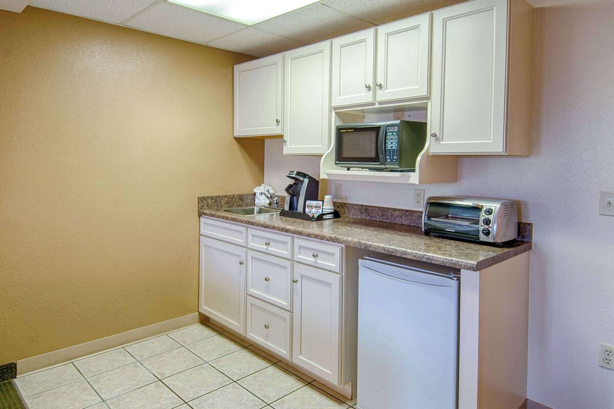 A small kitchenette with white cabinets, a microwave, a toaster, and a coffee maker.