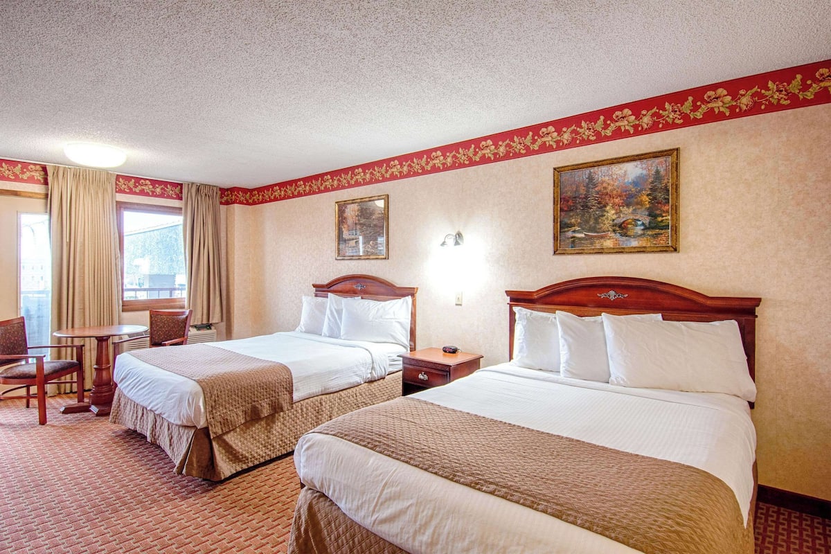 A hotel room with two beds, a desk, and a chair.