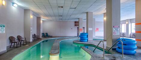 Una piscina interior con señales de seguridad, sillones de descanso y flotadores.