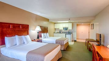 Habitación de hotel con dos camas, kitchenette, televisión y escritorio.