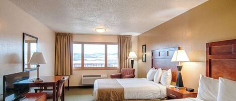 A hotel room with two beds, a desk with a TV, a chair, and a window with curtains.