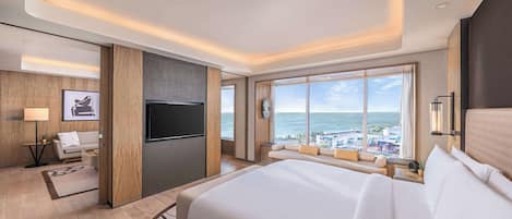 Habitación de hotel con una cama grande, televisión, sofá y vista al océano.