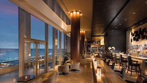 A modern bar area with seating and a view of the cityscape. - Conrad Manila (Pasay)