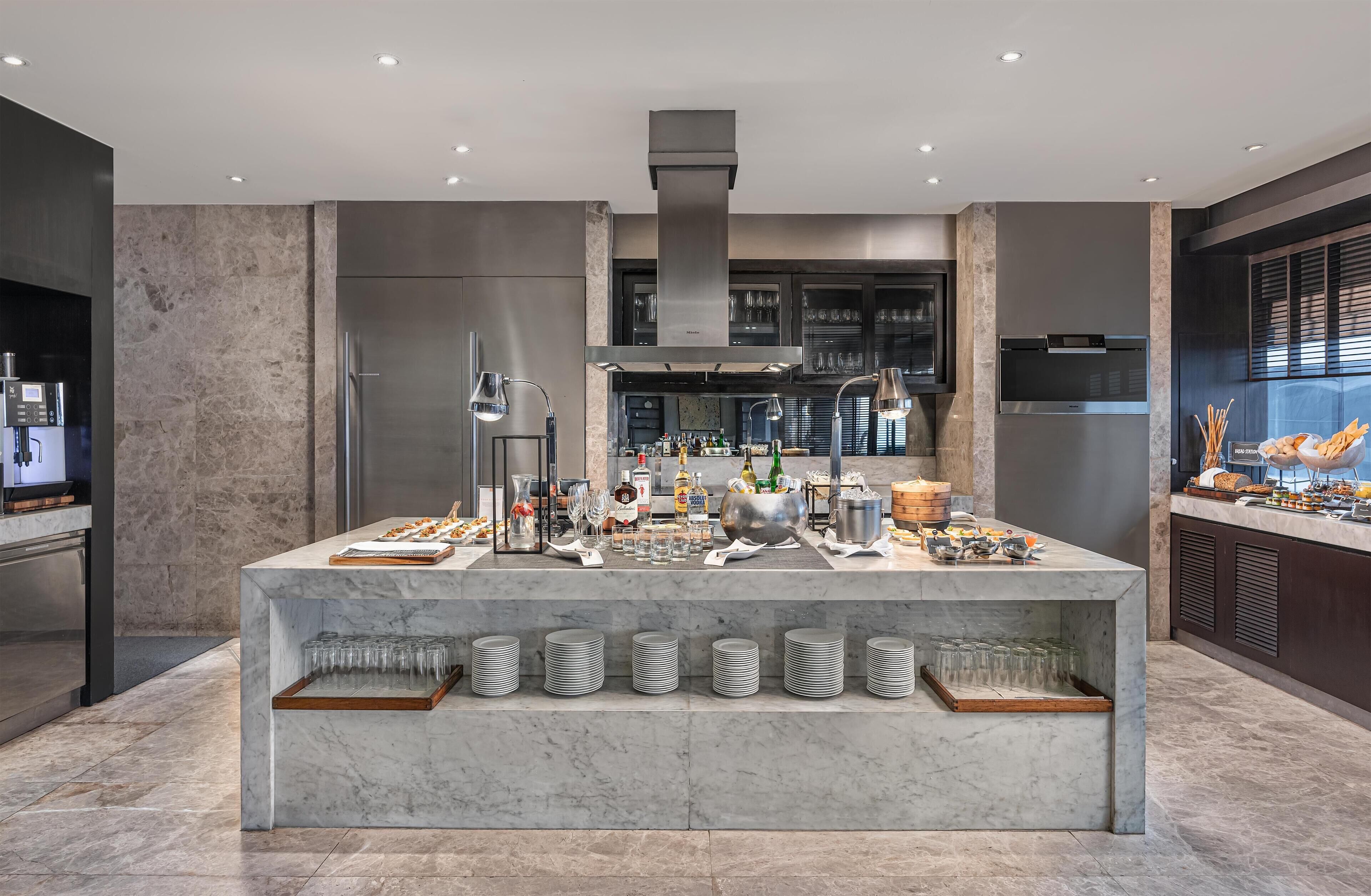 Una cocina moderna con una isla de mármol, electrodomésticos de acero inoxidable y una gran variedad de alimentos y bebidas.