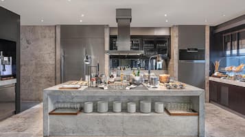 A modern kitchen with a marble island, stainless steel appliances, and a variety of food and drink items.