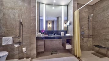 A modern bathroom with a large mirror, a shower, and a toilet.