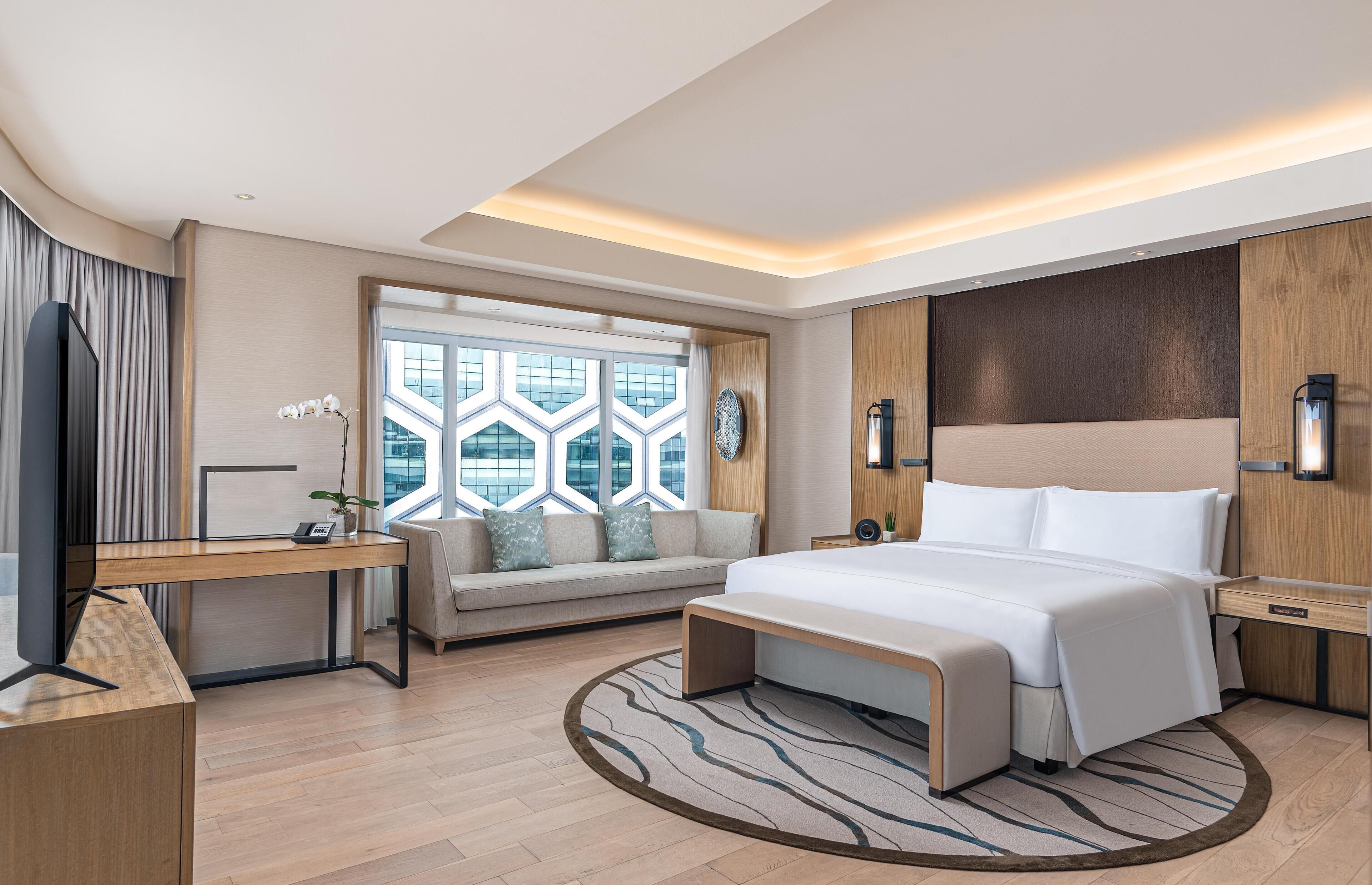 Une chambre d’hôtel moderne équipée d’un grand lit, d’un bureau, d’un canapé et d’une télévision.