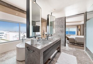 A modern bathroom with a large sink, mirrors, and a view of the city.