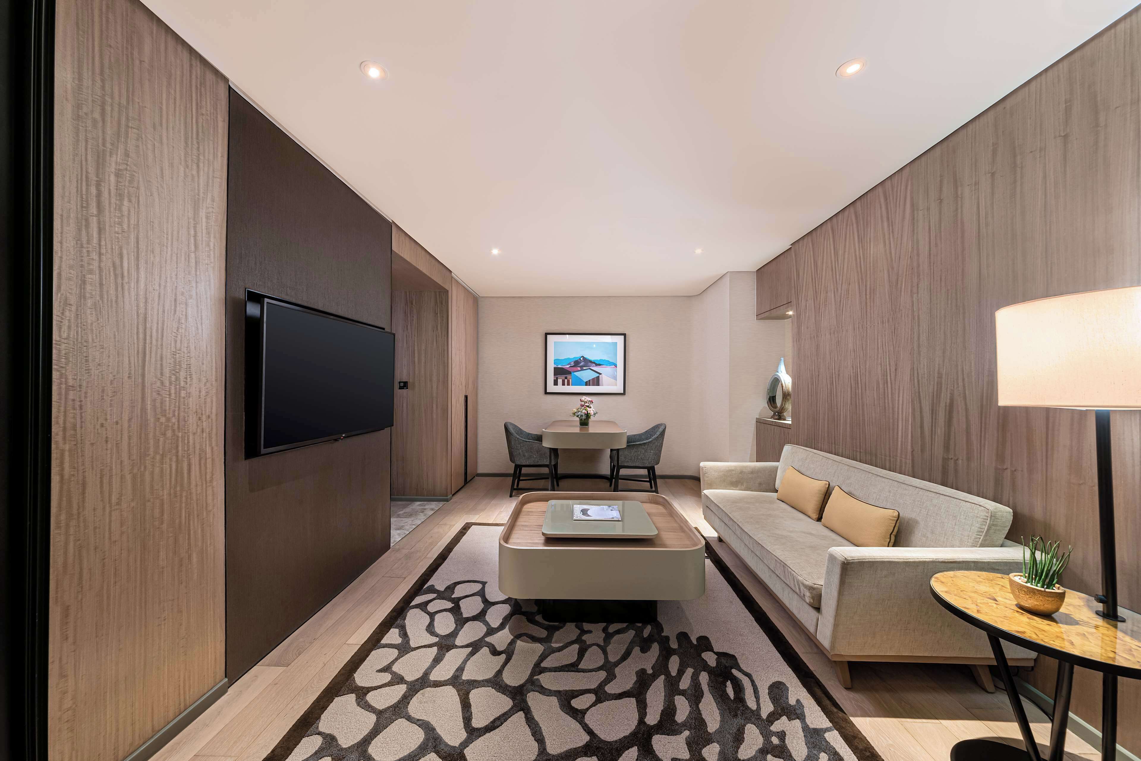 Una sala moderna con televisor de pantalla plana, un sofá, una mesita de centro y un comedor con dos sillas.