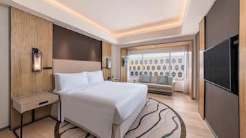 A modern hotel room with a large bed, bedside tables, a TV, and a view of a patterned exterior wall.