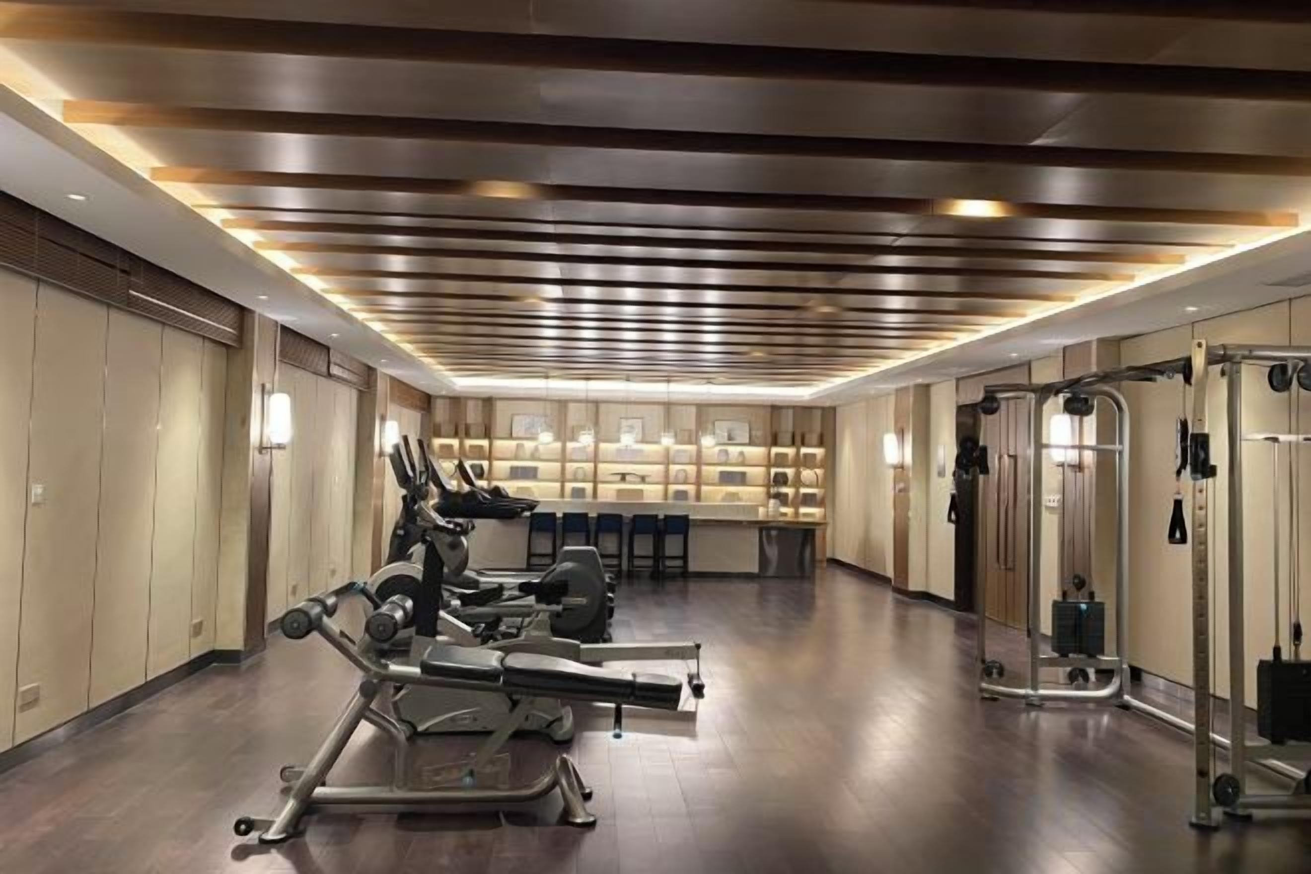 Un gimnasio con equipamiento de ejercicio, un espejo grande y una recepción.