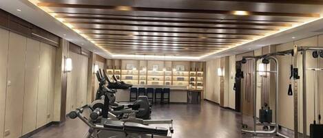 Un gimnasio con equipamiento de ejercicio, un espejo grande y una recepción.