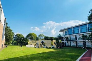A building with a flat roof, a large open grassy area, and a clear sky. - Longtan Lake Hotel (Shangrao)