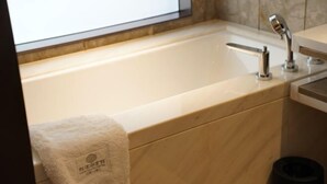 A modern bathroom with a bathtub, a towel, and a trash bin. - Longtan Lake Hotel (Shangrao)