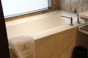 A modern bathroom with a bathtub, a towel, and a trash bin. - Longtan Lake Hotel (Shangrao)