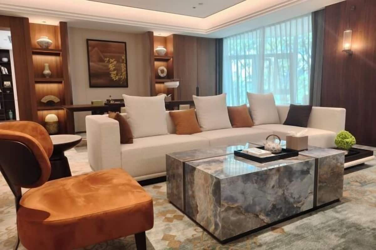 Un salon moderne avec un canapé blanc, une table basse en marbre et un fauteuil en cuir marron.