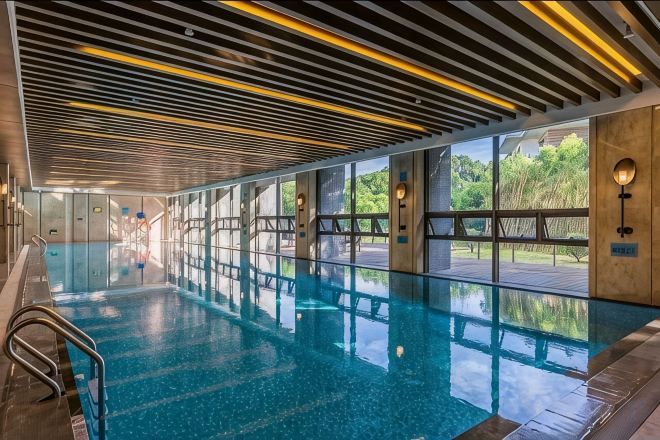 A swimming pool with a modern design, clear water, and a view of the outdoors.