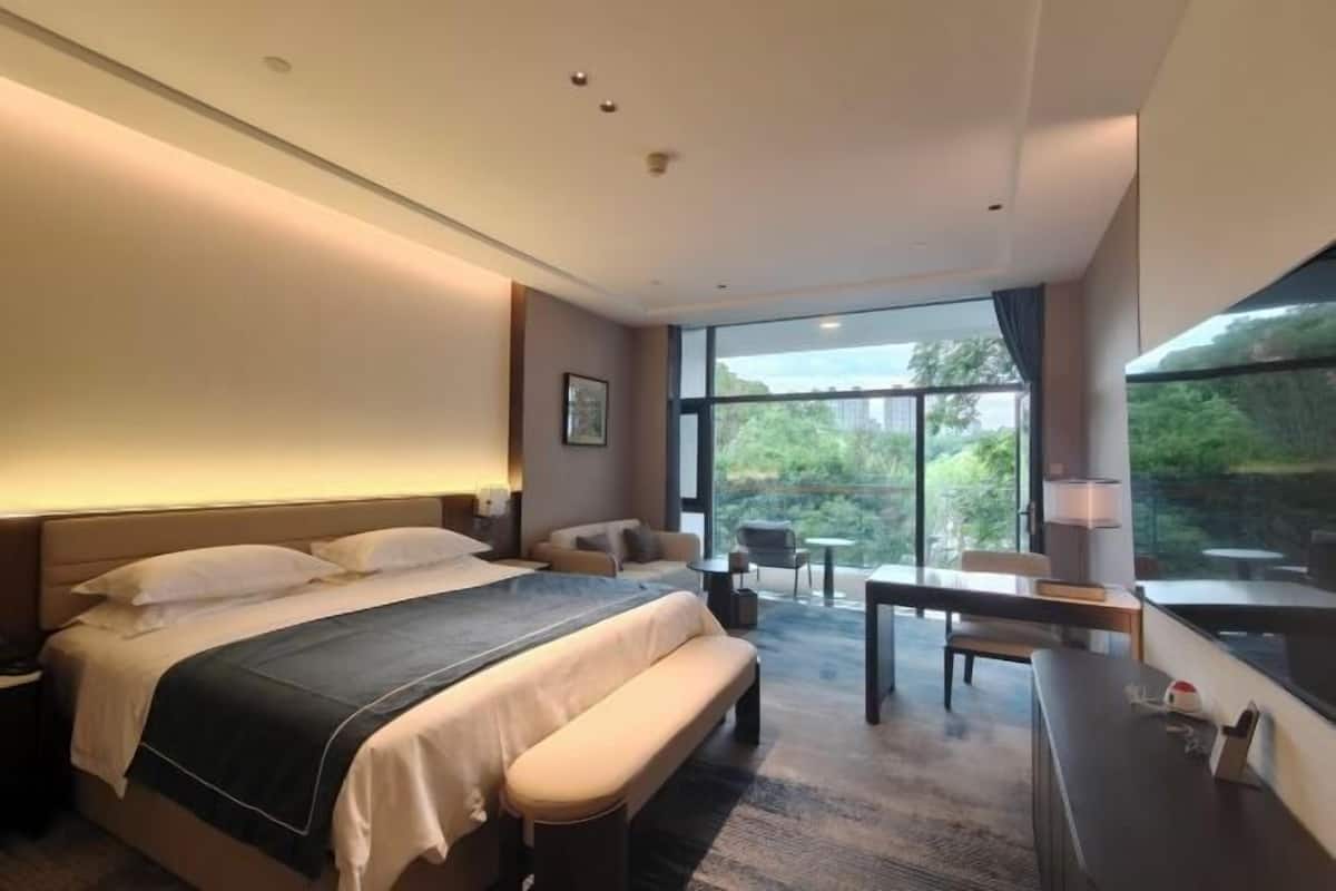 Une chambre d’hôtel moderne, dotée d’un grand lit, d’un bureau et offrant une vue sur l’extérieur.