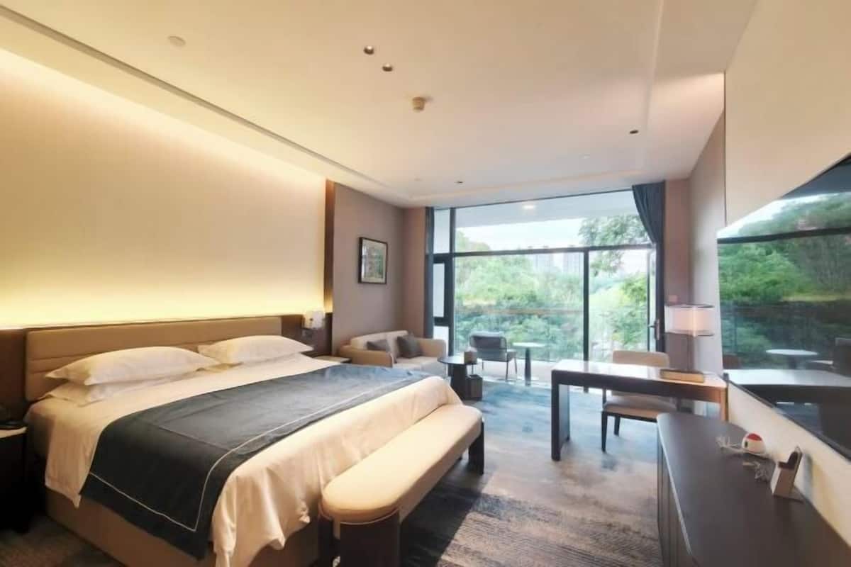 Une chambre d’hôtel moderne, dotée d’un grand lit, d’un bureau, d’une chaise et offrant une vue sur l’extérieur.