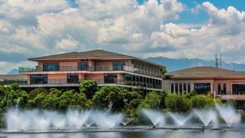 A modern building with a flat roof, large windows, and a water fountain in front.
