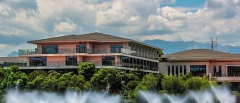A modern building with a flat roof, large windows, and a water fountain in front.