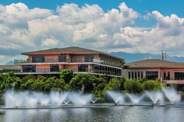 A modern building with a flat roof, large windows, and a water fountain in front. - Longtan Lake Hotel (Shangrao)