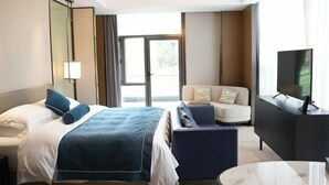 A hotel room with a bed, a sofa, a TV, and a large window. - Longtan Lake Hotel (Shangrao)