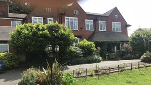 A residential area with a brick house, a garden with various plants, and a street lamp. - Barons Court Hotel (Wolverhampton)
