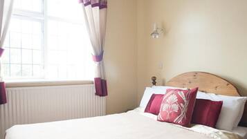 A bedroom with a bed, curtains, a chandelier, and a window.