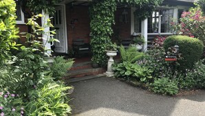 A house with a covered porch, a reception sign, and a garden with various plants and flowers. - Barons Court Hotel (Wolverhampton)