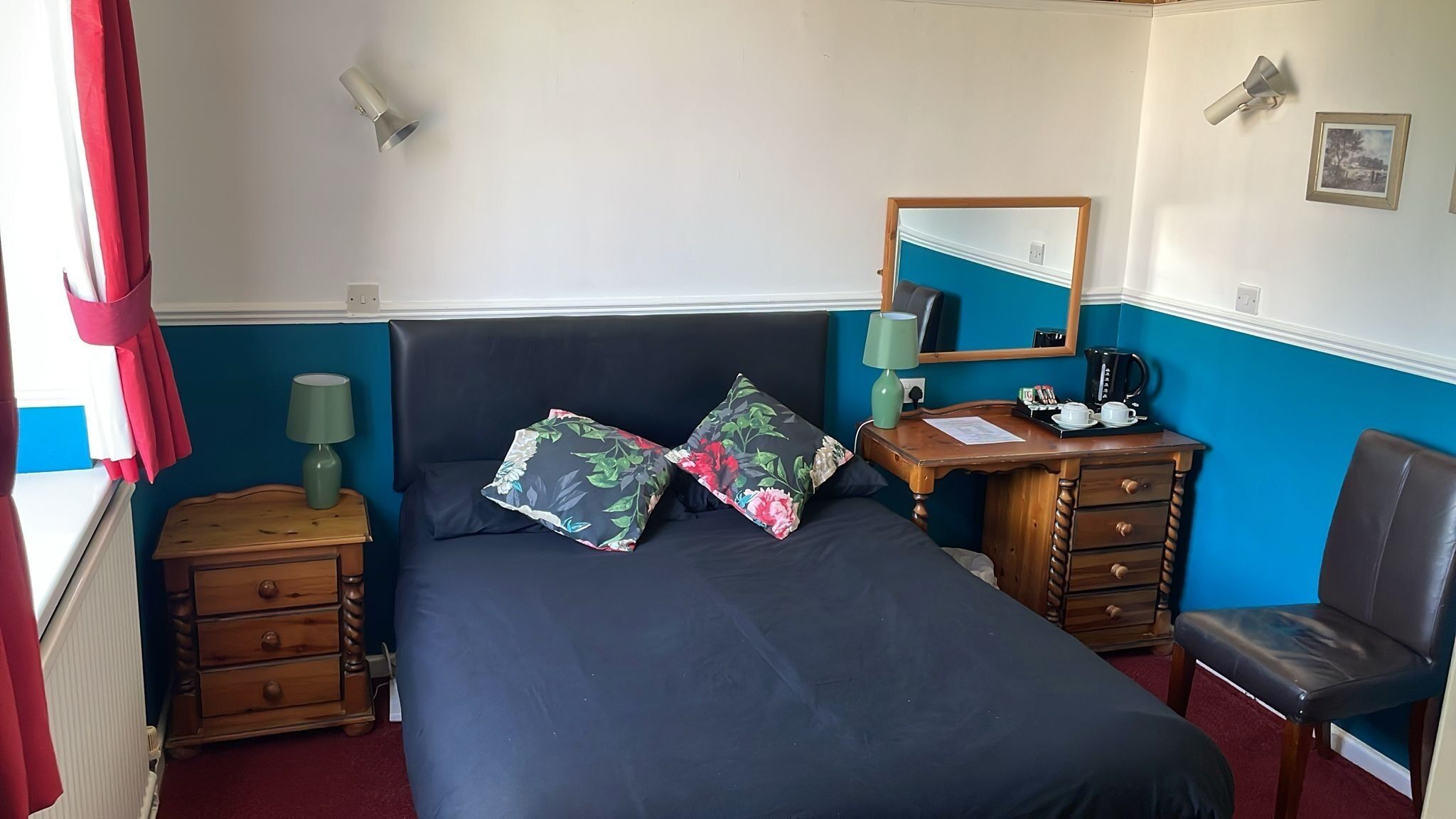 Een netjes opgemaakt slaapkamer met een bed, een kast, een stoel en een bureau met een spiegel.