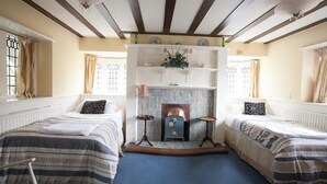 A room with two beds, a fireplace, and a shelf with decorative items. - Barons Court Hotel (Wolverhampton)