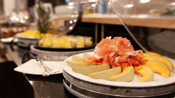 A buffet with various food items including melon slices and prosciutto.