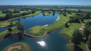An aerial view of a golf course with multiple ponds, sand bunkers, and lush greenery. - Hotel Diamond Country Club (Atzenbrugg)