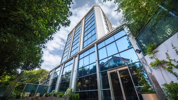 A modern building with large glass windows and a courtyard with seating and plants. -  Monapart Hotel Istanbul Mecidiyekoy (Istanbul)