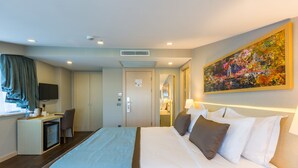 A hotel room with a large bed, a desk with a computer, a TV, and a painting on the wall. -  Monapart Hotel Istanbul Mecidiyekoy (Istanbul)