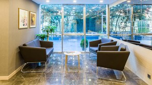 A modern waiting area with leather sofas, a small round table, and large windows offering a view of the outdoors. -  Monapart Hotel Istanbul Mecidiyekoy (Istanbul)